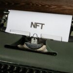 Close-up of a vintage typewriter with the word 'NFT' typed on paper, symbolizing digital innovation.