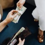 Close-up of hands exchanging cash, representing a financial transaction or payment.