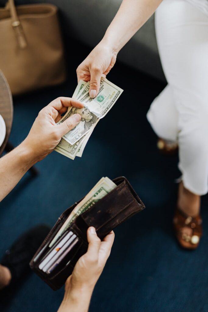 Close-up of hands exchanging cash, representing a financial transaction or payment.