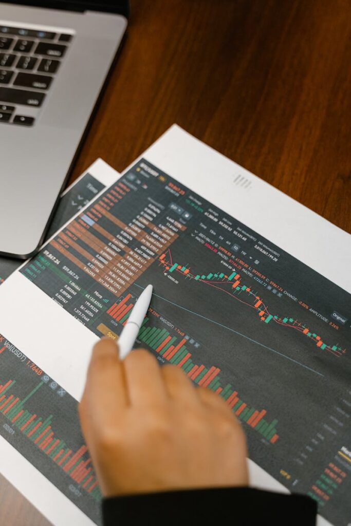 Close up of a person analyzing cryptocurrency graphs on printed charts.