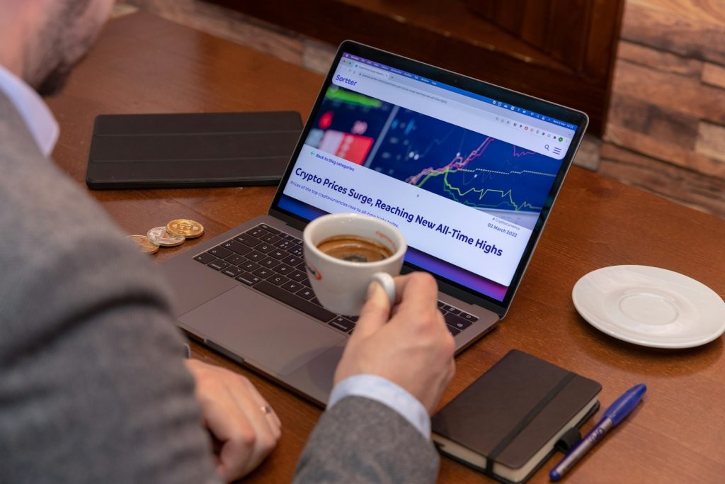 a man sitting at a table with a laptop and a cup of coffee