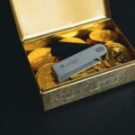 a swiss army knife sitting in a box of gold coins