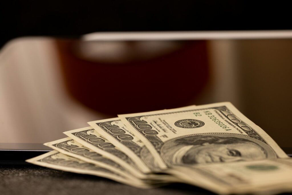 a stack of money sitting on top of a laptop computer