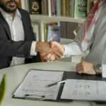 a couple of men shaking hands over a desk