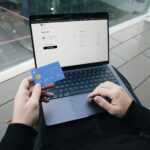 A person sitting in a chair with a laptop and a credit card