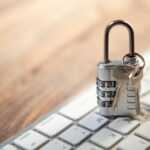 Padlock and keys resting on a computer keyboard.